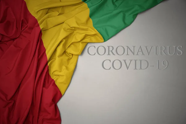 在灰色的背景上挥动着五彩缤纷的几内亚国旗 文字上写着Coronavirus Covid — 图库照片