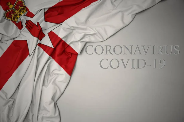 Mávání Barevnou Národní Vlajkou Severního Irska Šedém Pozadí Textem Coronavirus — Stock fotografie
