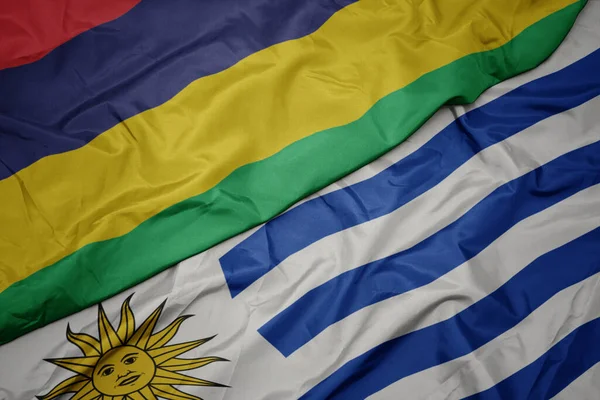waving colorful flag of uruguay and national flag of mauritius. macro