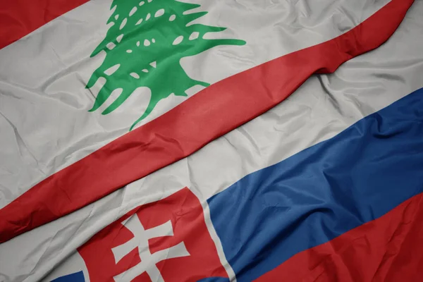 waving colorful flag of slovakia and national flag of lebanon. macro