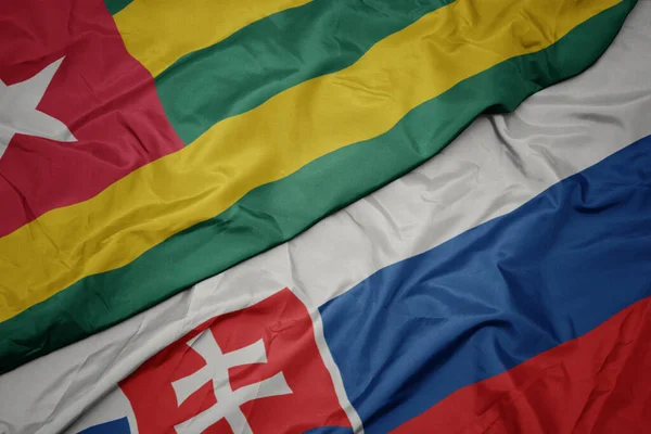 waving colorful flag of slovakia and national flag of togo. macro