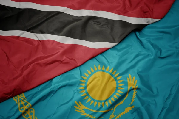 waving colorful flag of kazakhstan and national flag of trinidad and tobago. macro