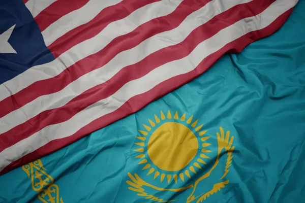 waving colorful flag of kazakhstan and national flag of liberia. macro