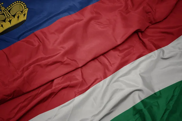 waving colorful flag of hungary and national flag of liechtenstein. macro