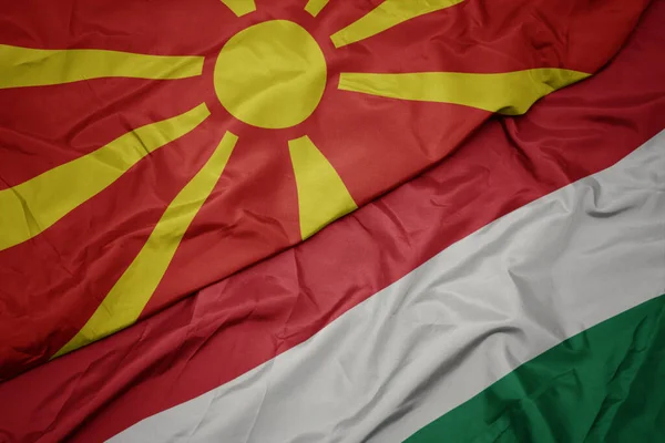 waving colorful flag of hungary and national flag of macedonia. macro