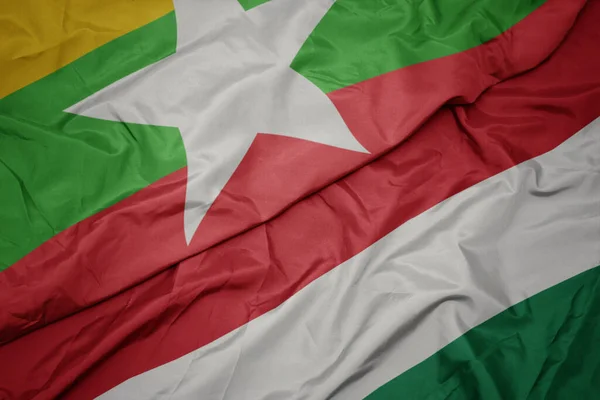 waving colorful flag of hungary and national flag of myanmar. macro