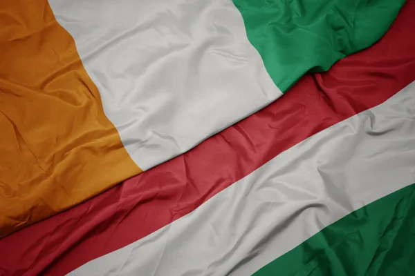ハンガリーのカラフルな旗とコート ディビオールの国旗を振っています マクロ — ストック写真