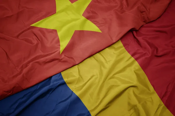 waving colorful flag of romania and national flag of vietnam. macro