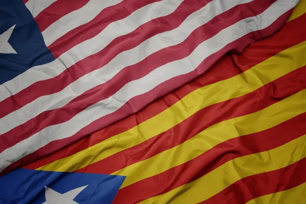 waving colorful flag of catalonia and national flag of liberia. macro