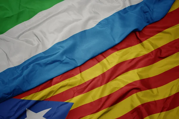 挥动着五彩缤纷的加泰罗尼亚国旗和塞拉里昂国旗 — 图库照片