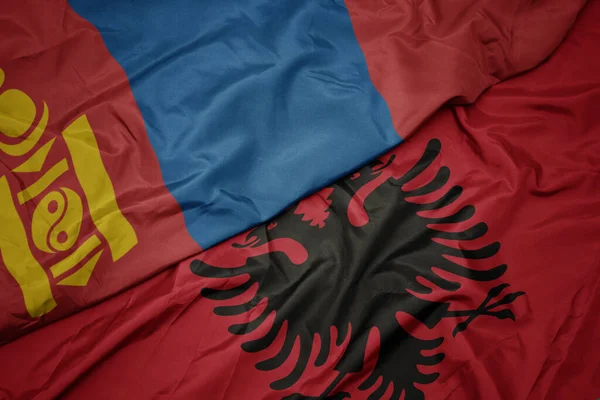 waving colorful flag of albania and national flag of mongolia. macro
