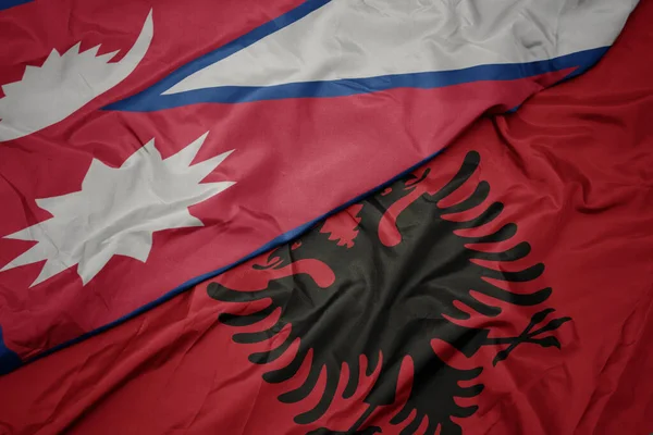 waving colorful flag of albania and national flag of nepal. macro
