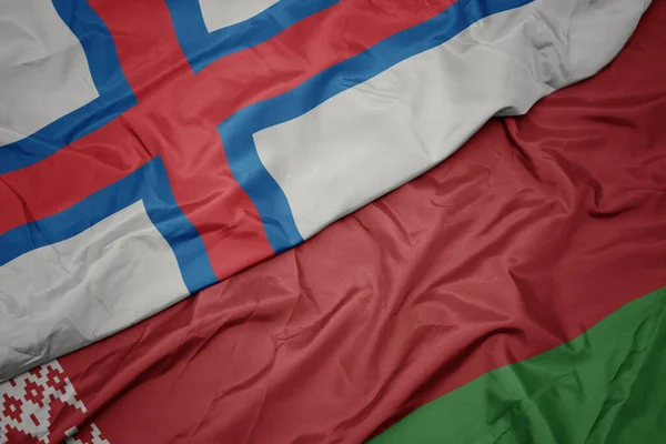 waving colorful flag of belarus and national flag of faroe islands. macro