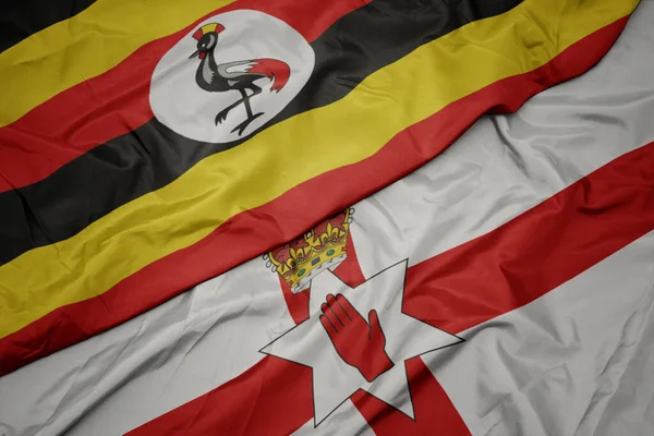 北アイルランドのカラフルな旗とウガンダの国旗を振っています マクロ — ストック写真