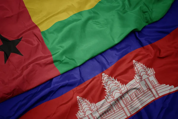 waving colorful flag of cambodia and national flag of guinea bissau. macro