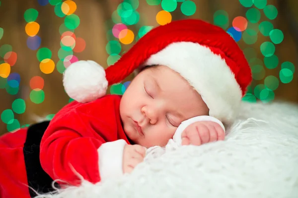 Portret van de pasgeboren baby in Santa kleren liggen onder kerstboom. — Stockfoto