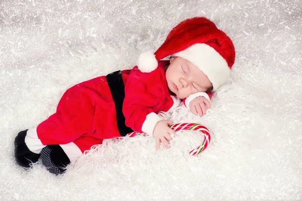 Porträt eines neugeborenen Babys in Weihnachtsmannkleidung, das unter dem Weihnachtsbaum liegt. — Stockfoto