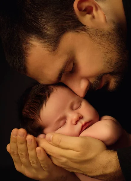 Pequeno bebê de 15 dias deitado de forma segura nos braços de seus pais, contra um fundo preto — Fotografia de Stock