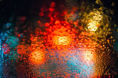 Sokak lambalarıyla pencereye yağmur damlaları yağar.