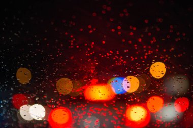 Sokak lambalarıyla pencereye yağmur damlaları yağar.