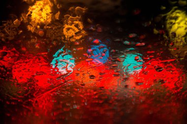 Sokak lambalarıyla pencereye yağmur damlaları yağar.