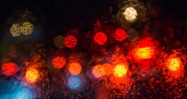 Sokak lambalarıyla pencereye yağmur damlaları yağar.