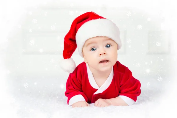 Смешной рождественский ребенок в костюме Санта-Клауса лежит на белом фоне — стоковое фото