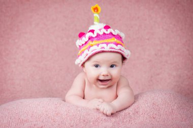 Newborn baby in warm knitted hat the form of cake with a candle clipart