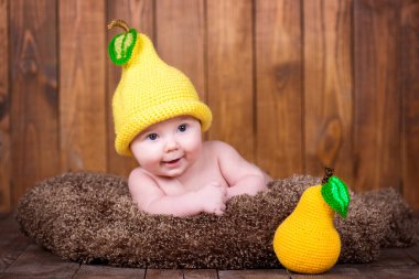 Newborn baby in a knitted cap the form of pear. clipart