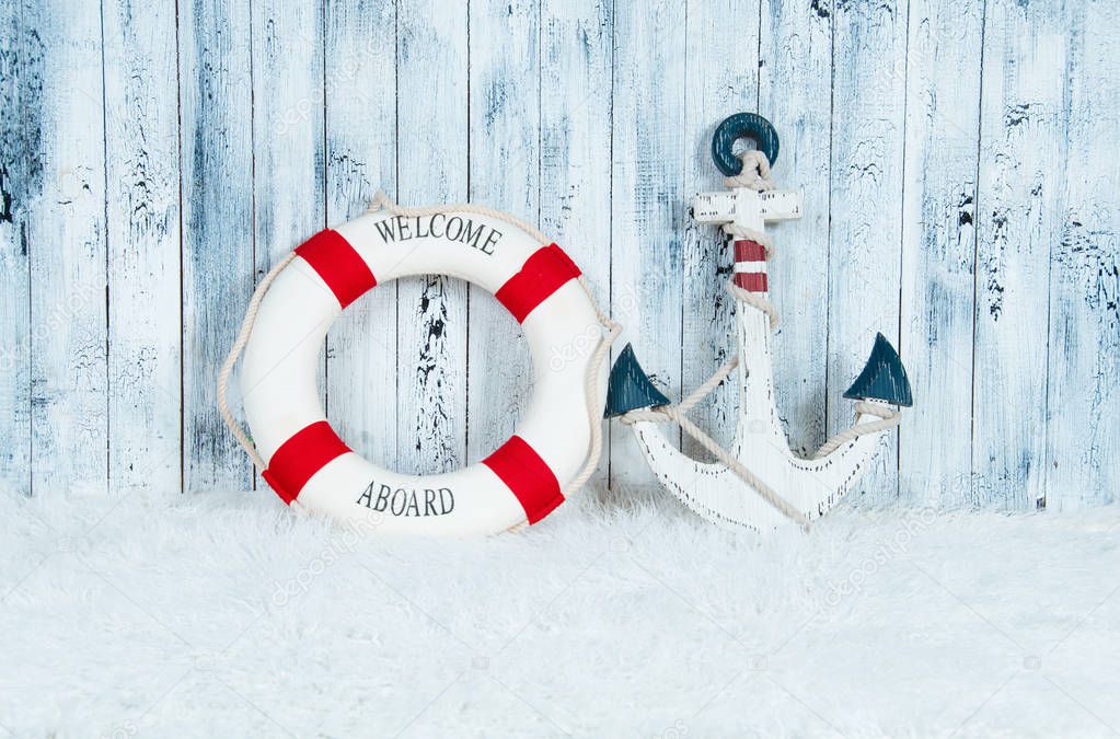 Decorative lifebuoy, anchor and starfish sea shells over wooden blue background