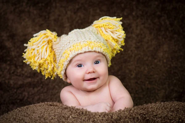 Newborn in knitted winter hat on a beige background. — Stock Photo, Image