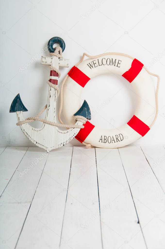 Anchor and life buoy on a white wooden floor