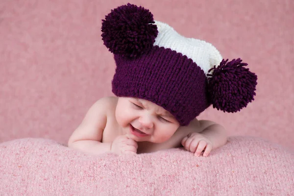 Beautiful little girl crying in the knitted cap on a pink background. — Stock Photo, Image