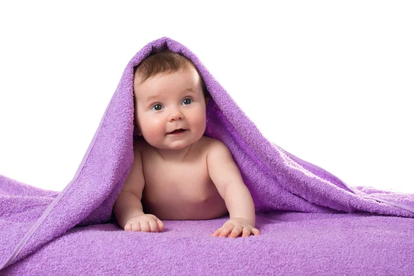 Новорожденный ребенок лежит и улыбается в фиолетовом полотенце — стоковое фото