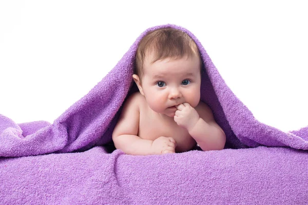 Newborn baby lying down and smiling in a purple towel — Stock Photo, Image