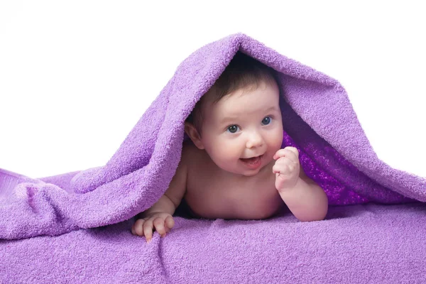 Bebê recém-nascido deitado e sorrindo em uma toalha roxa — Fotografia de Stock