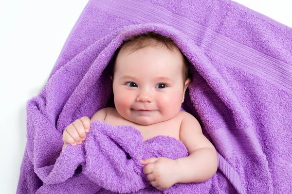 Bebê recém-nascido deitado e sorrindo em uma toalha roxa — Fotografia de Stock