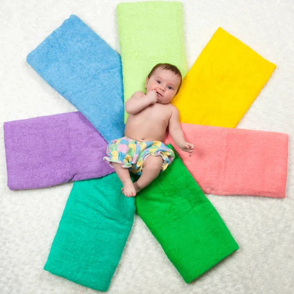 Nyfödda barnet ligger på flerfärgade handdukar. Lycka — Stockfoto