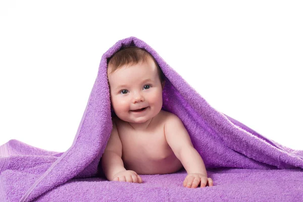 Newborn baby lying down and smiling in a purple towel — Stock Photo, Image