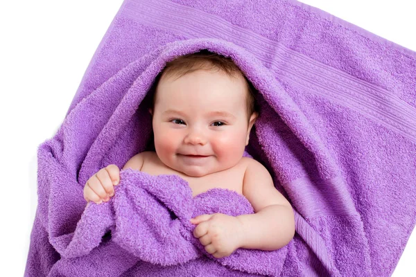 Newborn baby lying down and smiling in a purple towel — Stock Photo, Image