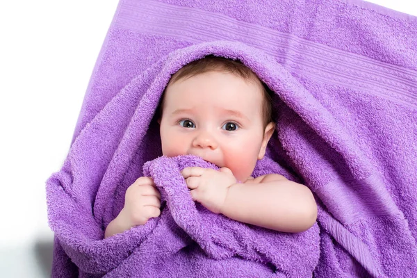 Новорожденный ребенок лежит и улыбается в фиолетовом полотенце — стоковое фото