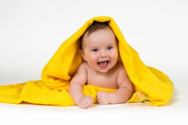 Aşağı uzanmış ve sarı bir havlu ile gülümseyen yeni doğan bebek