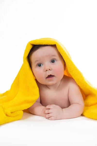 Newborn baby lying down and smiling in a yellow towel — Stock Photo, Image