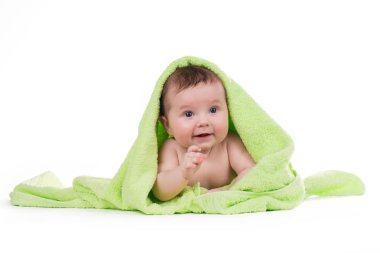 Aşağı uzanmış ve yeşil bir havlu ile gülümseyen yeni doğan bebek.