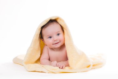 Aşağı uzanmış ve sarı bir havlu ile gülümseyen yeni doğan bebek