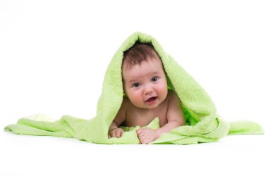 Aşağı uzanmış ve yeşil bir havlu ile gülümseyen yeni doğan bebek.
