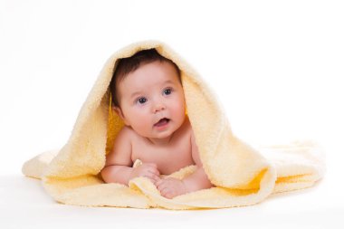 Aşağı uzanmış ve sarı bir havlu ile gülümseyen yeni doğan bebek