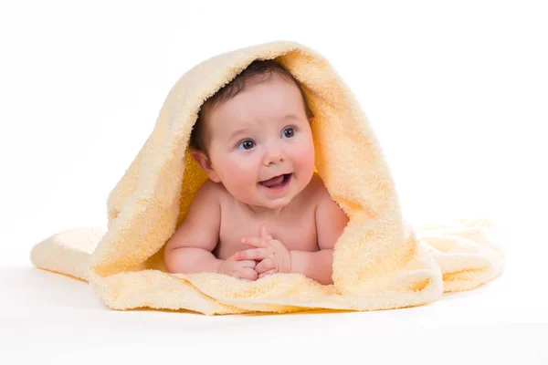 Новорожденный ребенок лежит и улыбается в желтом полотенце — стоковое фото