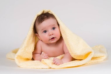 Aşağı uzanmış ve sarı bir havlu ile gülümseyen yeni doğan bebek