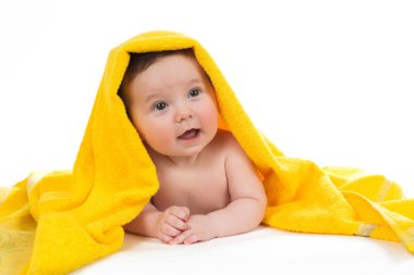 Aşağı uzanmış ve sarı bir havlu ile gülümseyen yeni doğan bebek